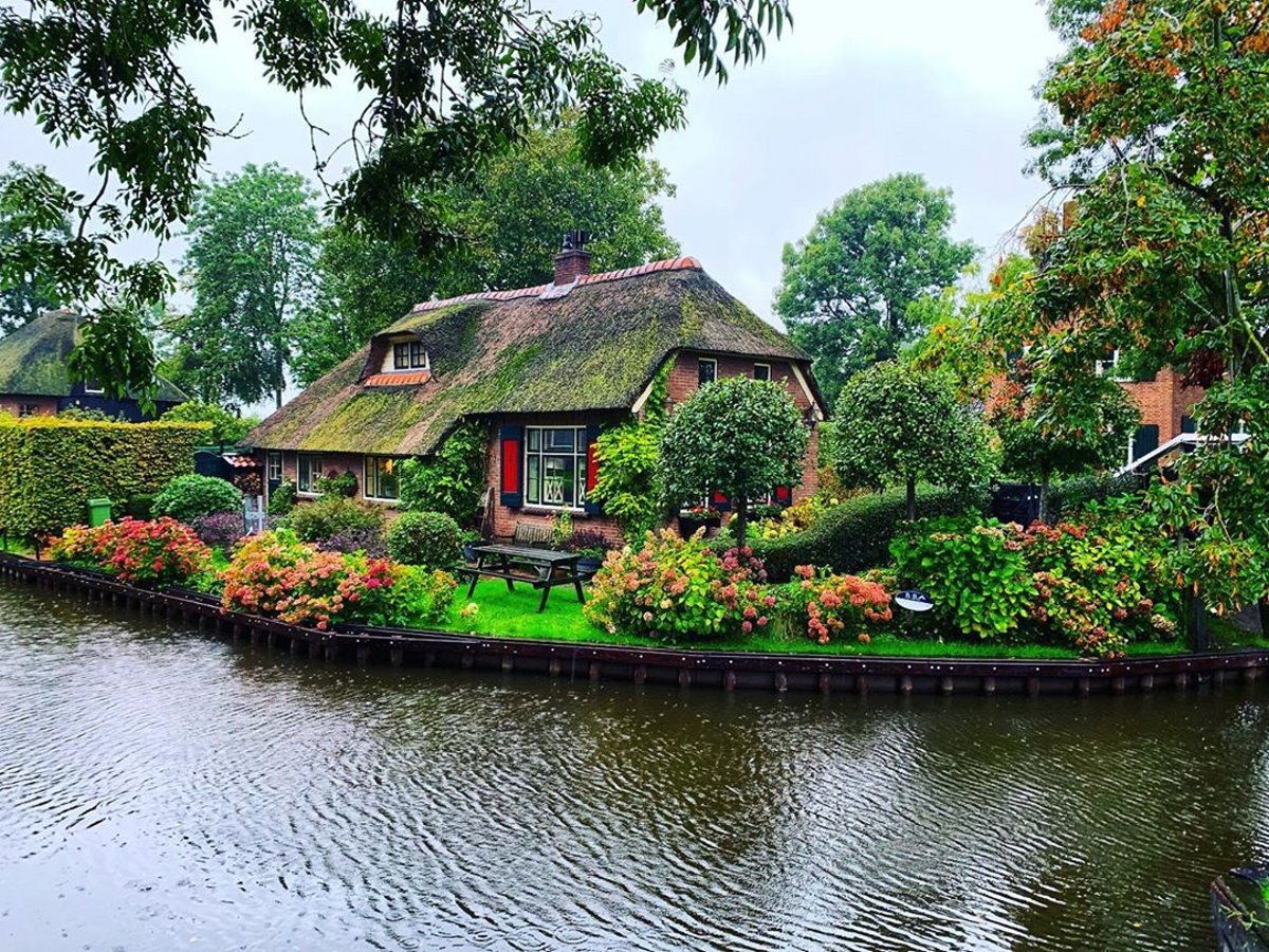Giethoorn χωριό Ολλανδίας σπίτι σε ποτάμι με πράσινο κήπο