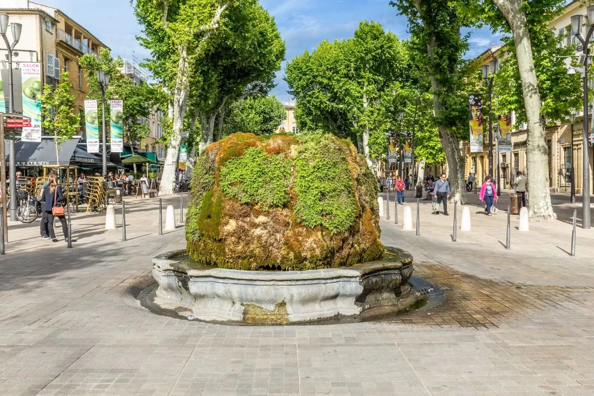 Άνθρωποι στο cours Mirabeau στο nine cannon σιντριβάνι στην Aix en Provence - Τα γλυπτά δεν είναι ορατά λόγω της βλάστησης από βρύα.