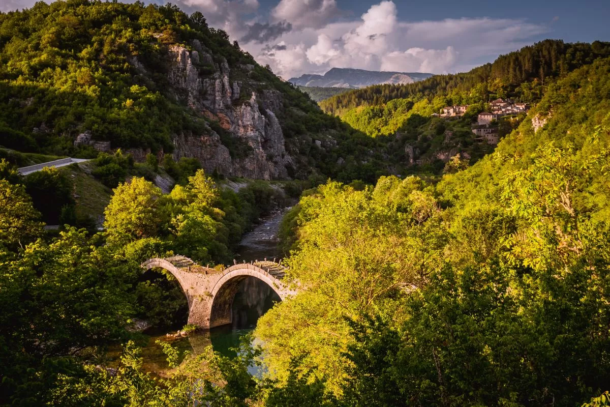 Γέφυρα Πλακίδα με φόντο το χωριό Κήποι. Πέτρινο γεφύρι Καλογερικού στον ποταμό Βοϊδομάτη. Κεντρικό Ζαγόρι