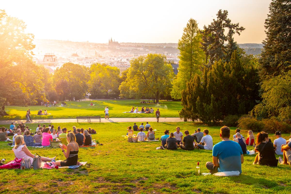 Ηλιοβασίλεμα στους κήπους Rieger, Riegrovy sady, στην Πράγα. Πολλοί άνθρωποι κάθονται στο γρασίδι και απολαμβάνουν το ηλιόλουστη καλοκαιρινή μέρα κοιτάζοντας την ιστορική πόλη της Πράγας